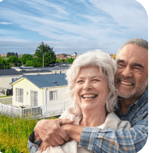 A happy retired couple at a UK holiday park, with caravans in the background.